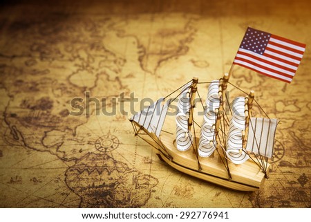 Sailboat model with flag on ancient world map, vintage light tone