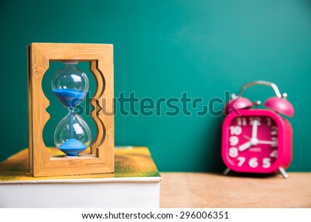 sand glass and book with green board background