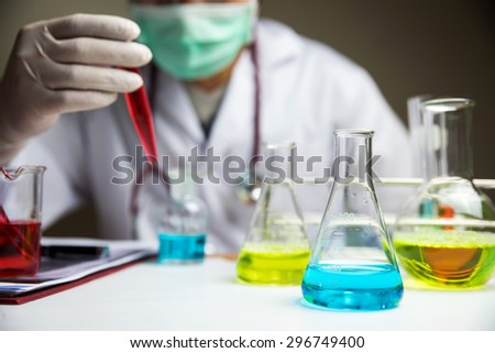 Laboratory research, lab glassware containing chemical with blur scientist