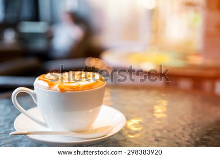 Cappuccino cup on the table, blur coffee shop background