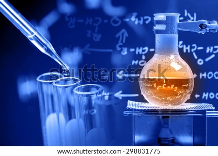 Dropping liquid to test tube with boiling chemical in round bottom flask, laboratory concept