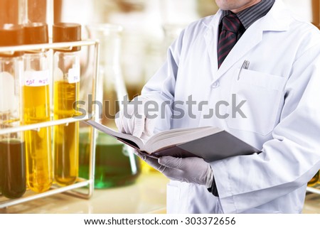 Doctor reading text book with test tubes background