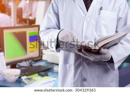 Doctor reading text book with blur lab equipment background