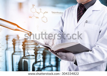 Doctor reading text book with blur test tubes background, laboratory concept
