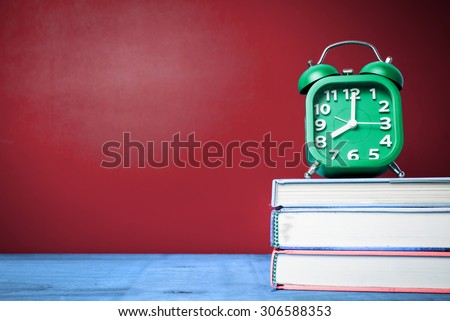 Retro alarm clock and text book with wood board background