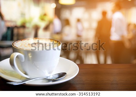 Cappuccino on the table with blur people in coffee shop background