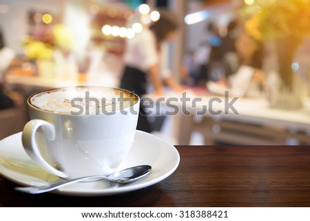 Cappuccino on the table with blur people in coffee shop background