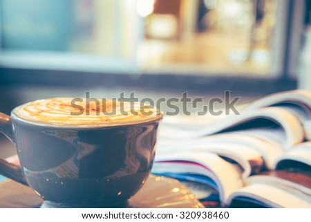 Cup of cappuccino with magazine on blur coffee shop background, vintage tone