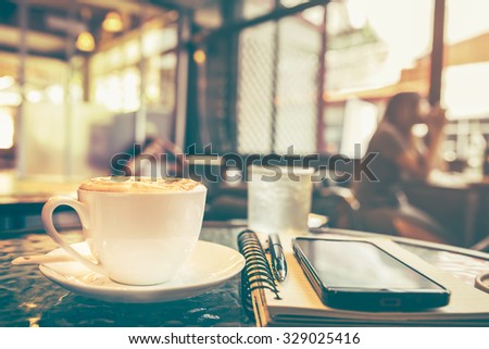 Cappuccino coffee on the table with blur coffee shop background, vintage tone