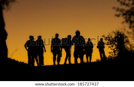 Black silhouettes of eight people against orange sky at sunset
