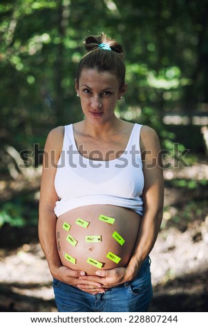 A pregnant woman protectively holding her belly with post its on it