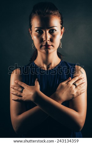 Serious woman protecting herself having crossed arms - isolated on black.