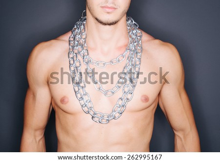 Torso of a man\'s muscular body with chains around his neck