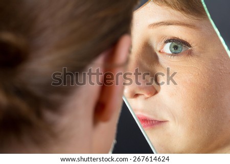 Blond girl with perfect face watching herself in the mirror