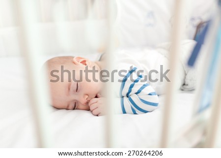 Innocence baby boy taking a nap in crib.
