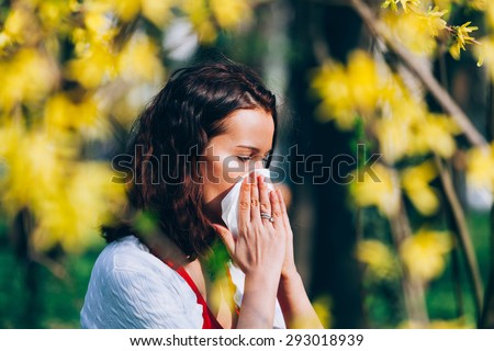 Cute girl in the park, sneezing, having spring allergies