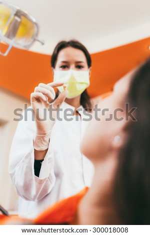 Woman dentist showing to her patient the tooth extracted