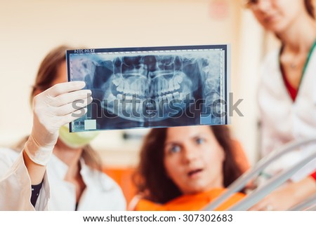 Shocked patient looking at tooth\'s x-ray hold by dentist\'s hand