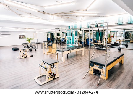 A gym full of pilates equipment: exochairs, ladder barrel, reformer, cadillac, trapeze table and other.