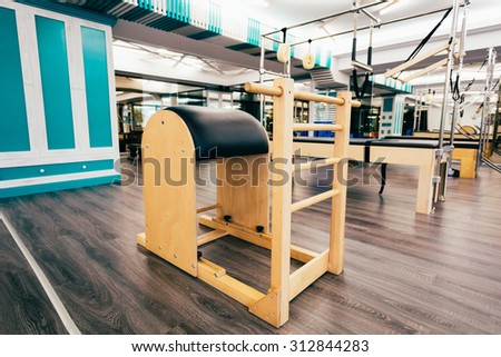 Pilates room with image focus on ladder barrel. Cadillac and other equipment in the background.