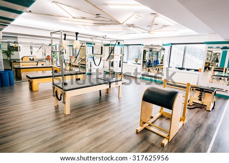 Room full of pilates equipment: exochairs, ladder barrel, reformer, cadillac and trapeze table