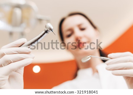 Dentist using drill to remove decay from the tooth. Dentist is in blur. Capture taken from the patient\'s position.