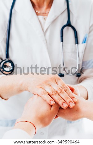 Doctor with stethoscope is holding hands of a female patient