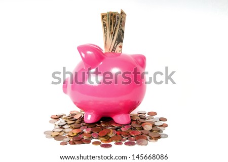 Pink Piggy bank sitting on coins with USD american bank notes coming out the top.