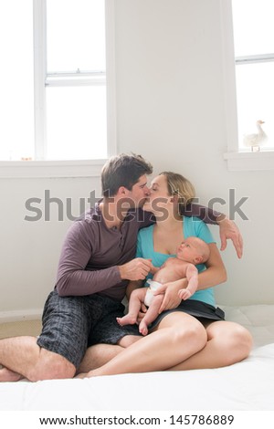 happy new parents with their newborn son kissing