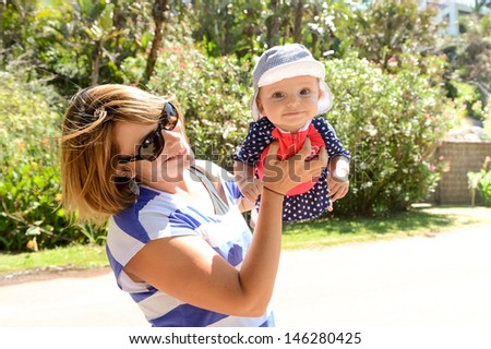 Mother excited about her daughters first day at the beach wearing a blue hat and pink and blue bathers