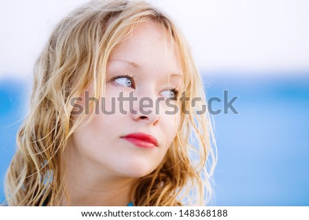 Close up Portrait of a Beautiful sexy young woman with blonde hair, pale skin, wonderful blue eyes and red lipstick in front of the sea