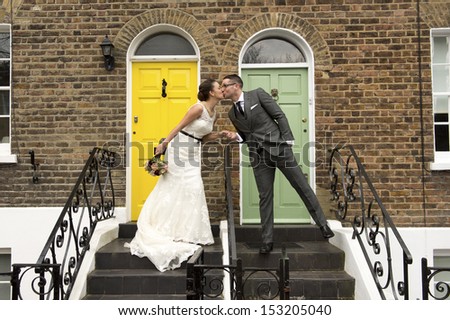 Happy couple kissing on their wedding day in front of their dream home in London