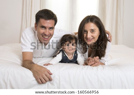 Young couple mother father and baby girl laying on bed isolated portrait