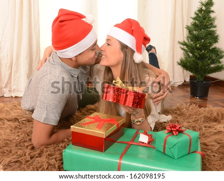 Romantic Young Happy Couple with Christmas Presents on rug at home