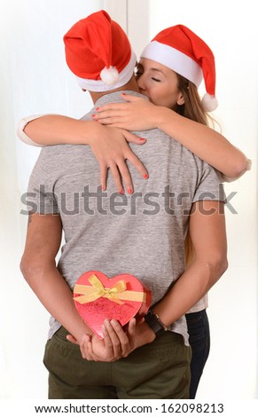 Romantic Young Happy Couple kissing and hidden Christmas Present isolated on white background