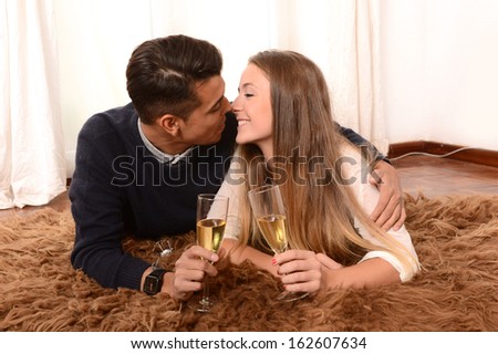 Happy Romantic Young Couple in Love drinking Champagne on Rug