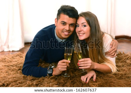 Happy Romantic Young Couple in Love drinking Champagne on Rug