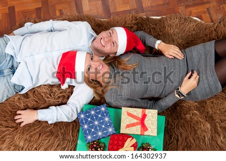 Romantic Young Happy Couple with Christmas Presents lying on rug