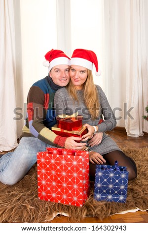 Romantic Young Happy Couple with Christmas Presents on rug at home