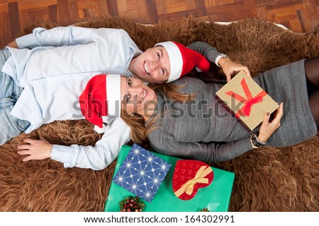 Romantic Young Happy Couple with Christmas Presents lying on rug