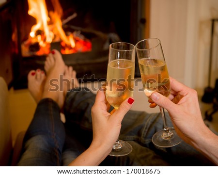 close up of young couple drinking champagne in front of a open wood fire