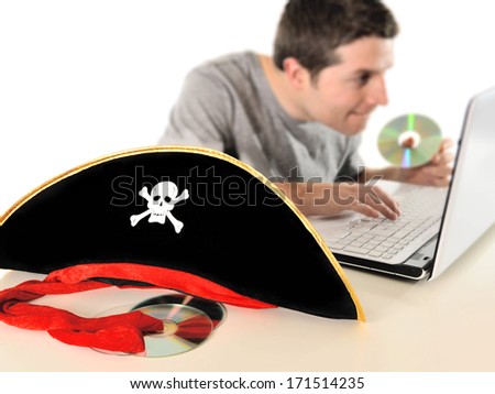 Young with Computer copying dvd and pirate hat representing illegal downloads and copyright violation isolated on white background