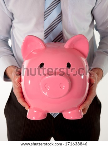 close-up of a giant pink piggy bank with a business man wear a blue shirt and blue tie in the background on a white background