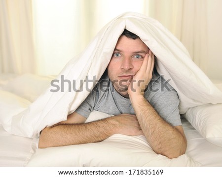 young man in bed with eyes opened suffering insomnia and sleep disorder thinking about his problem