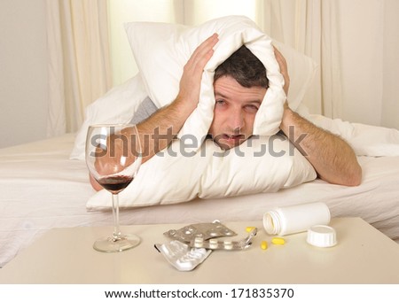 exhausted young Man in bed with coffee, water and tablets suffering hangover and headache