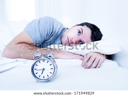 young man in bed with eyes opened suffering insomnia and sleep disorder thinking about his problem