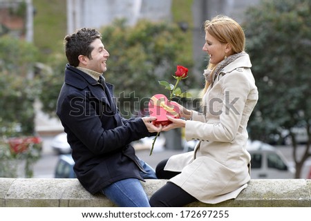 Romantic Man giving flower and heart shaped box to woman for valentines day