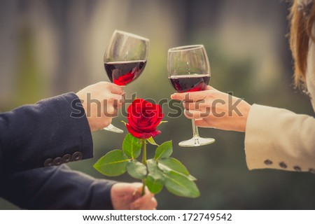 close up a romantic couple drinking wine with a rose in the mans hand on valentines day