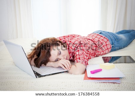 red haired student, business woman lying  asleep on her laptop on a white background