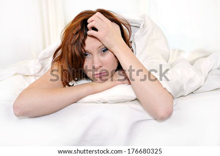 Young red hair woman on bed waking up with hangover and headache